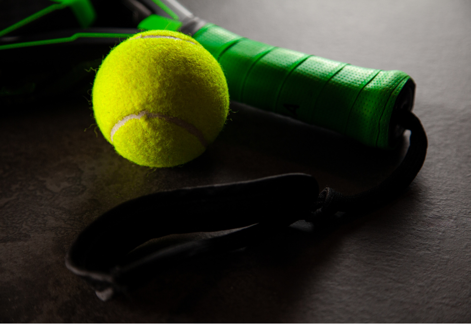 gros plan sur une balle et un manche de raquette de Padel vert.
