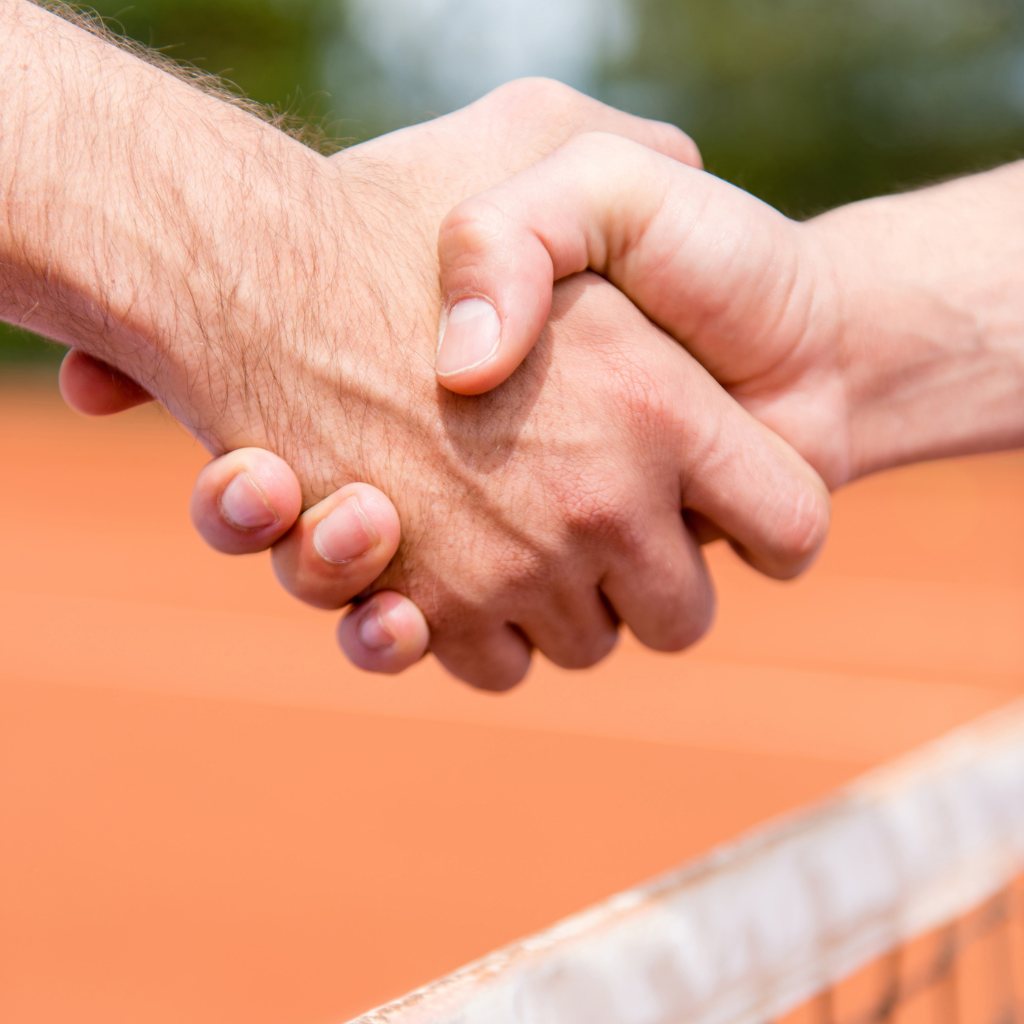 gros plan sur une poignée de mains entre deux personnes sur un court de padel